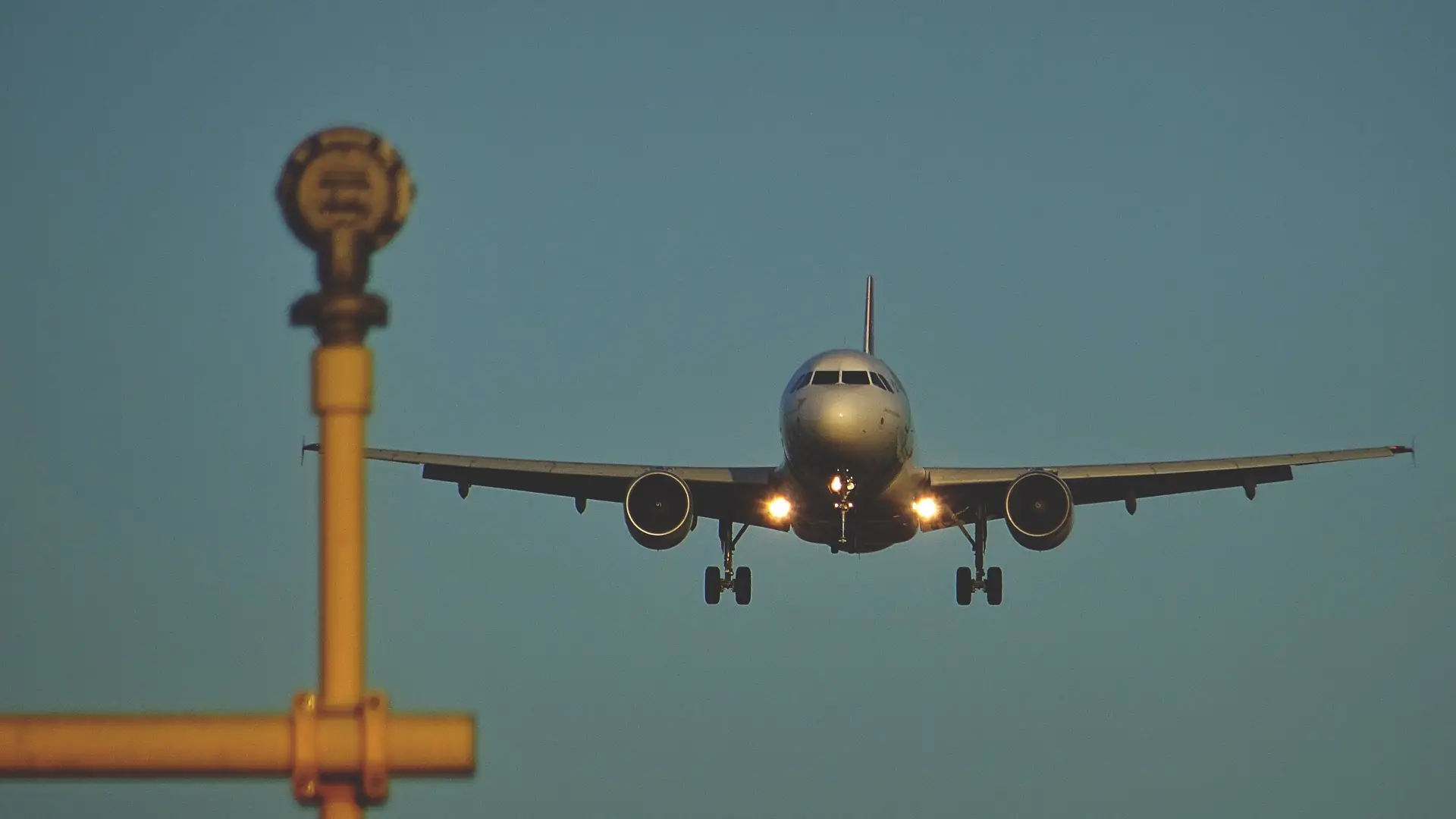 Commercial aircraft on final approach with landing lights on at dusk